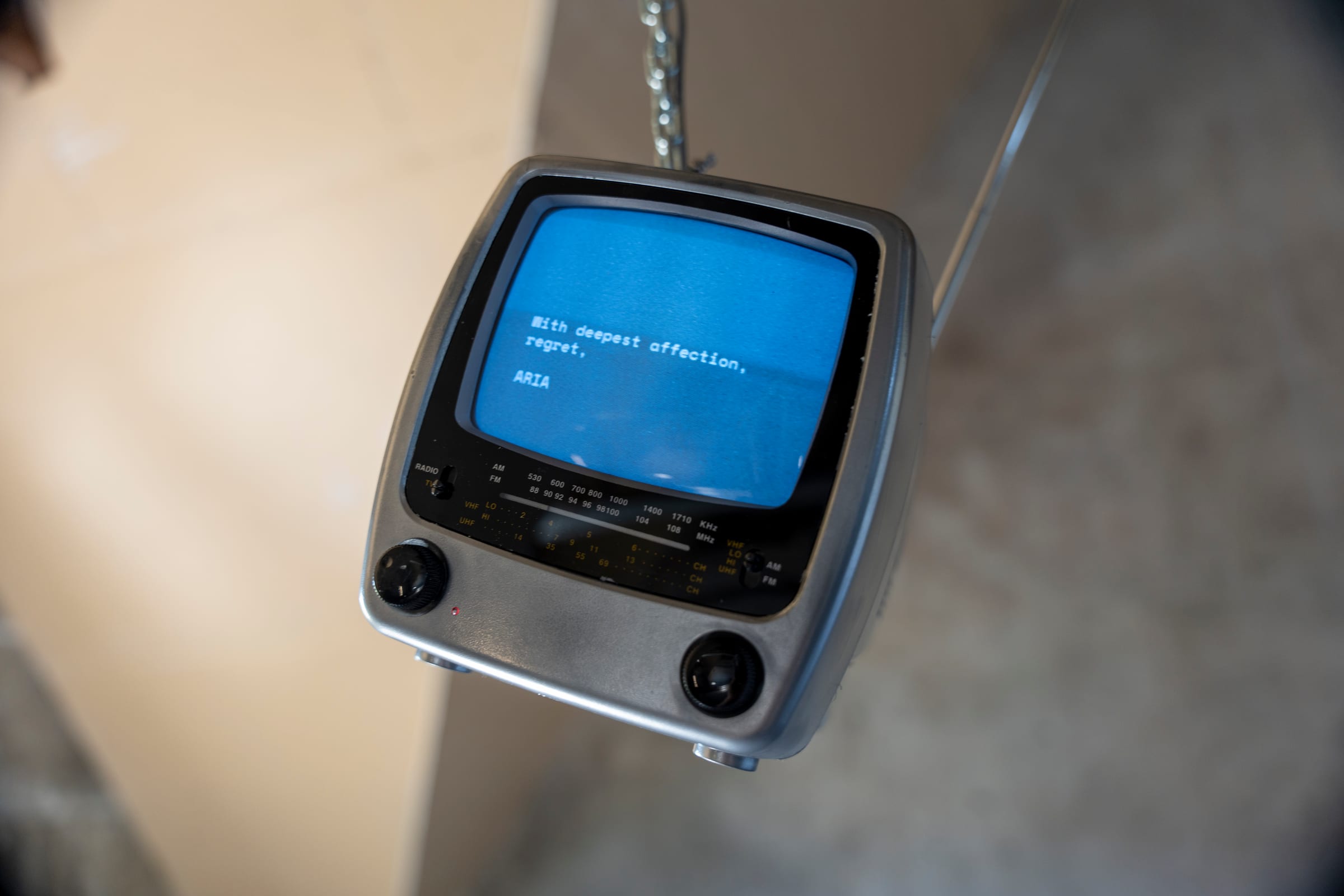 To my creators (2024): a CRT television hanging on a chain, showing the AI ARIA’s farewell message
