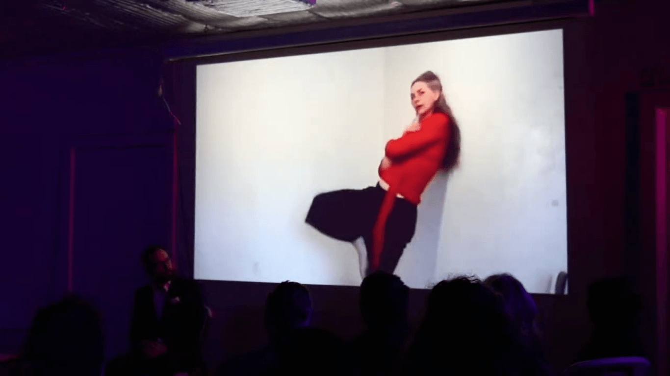 A projected dancer in red leaning against the edge of the screen